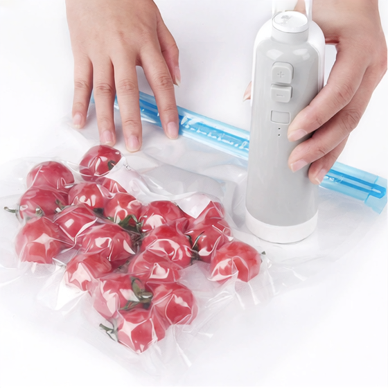 Portable kitchen vacuum sealer being used to keep strawberries fresh in a resealable vacuum bag